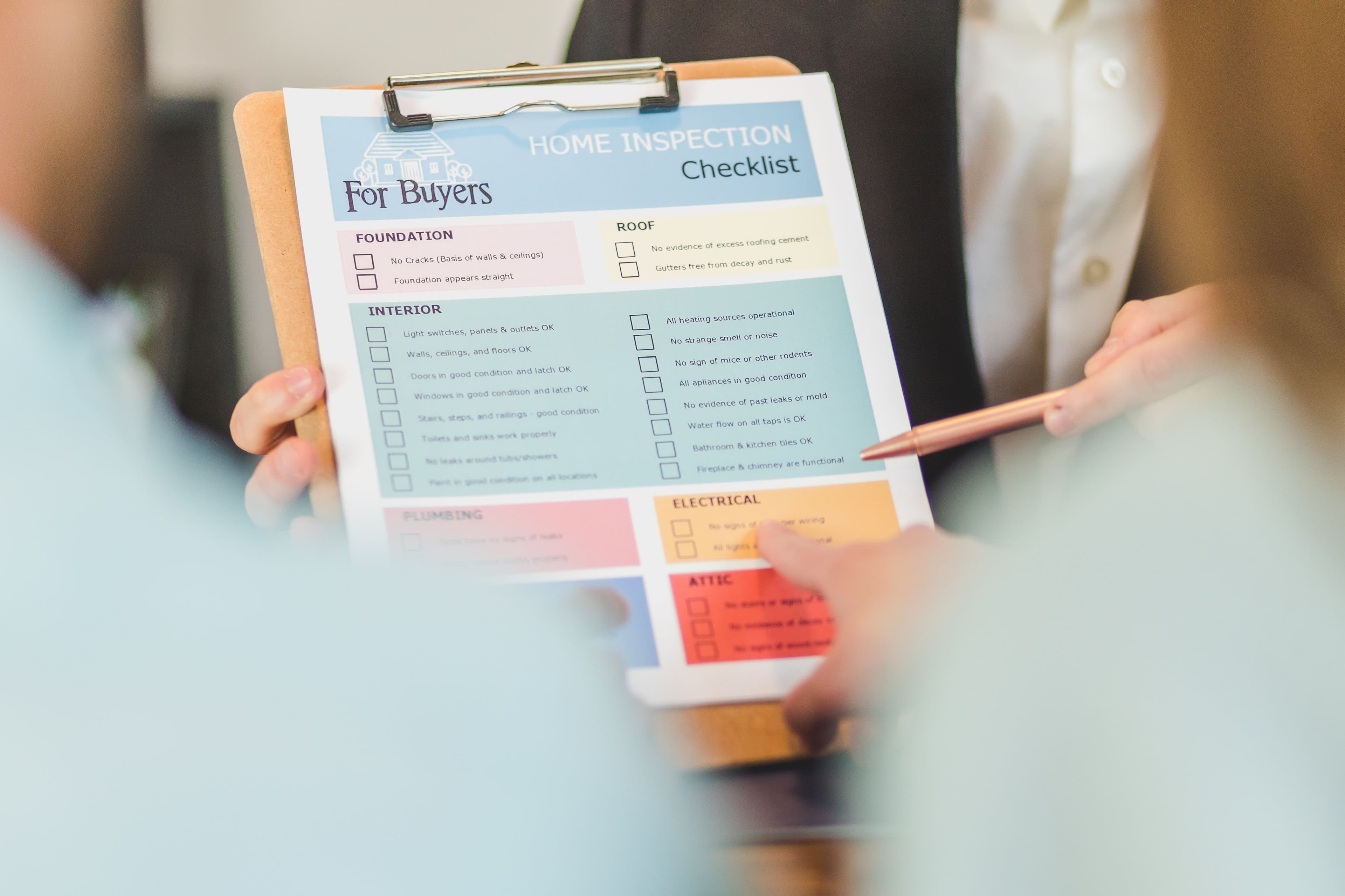 Close-up of hands holding a home inspection checklist clipboard for buyers.