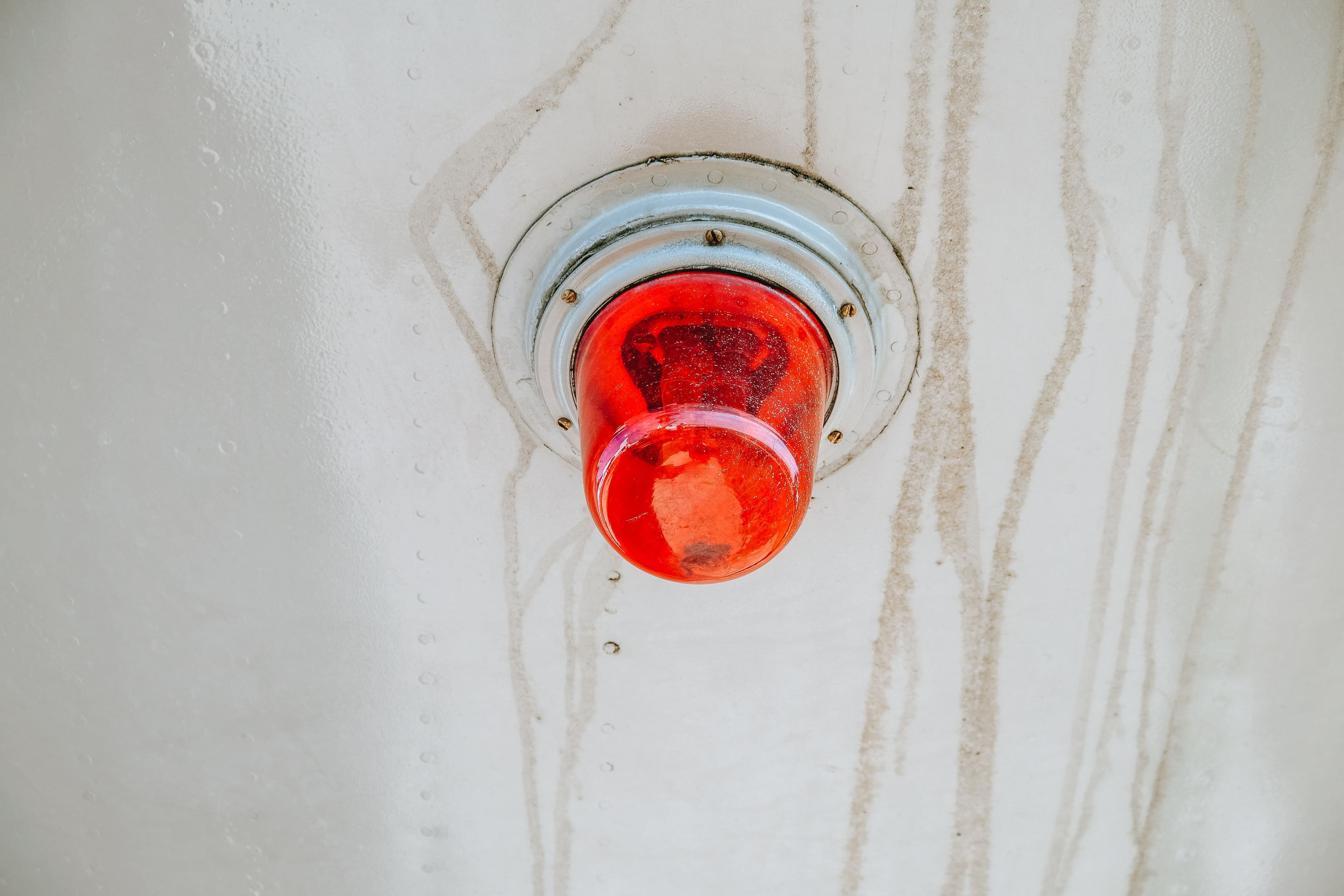 A red emergency warning light mounted on a metallic surface, often used for alerts.