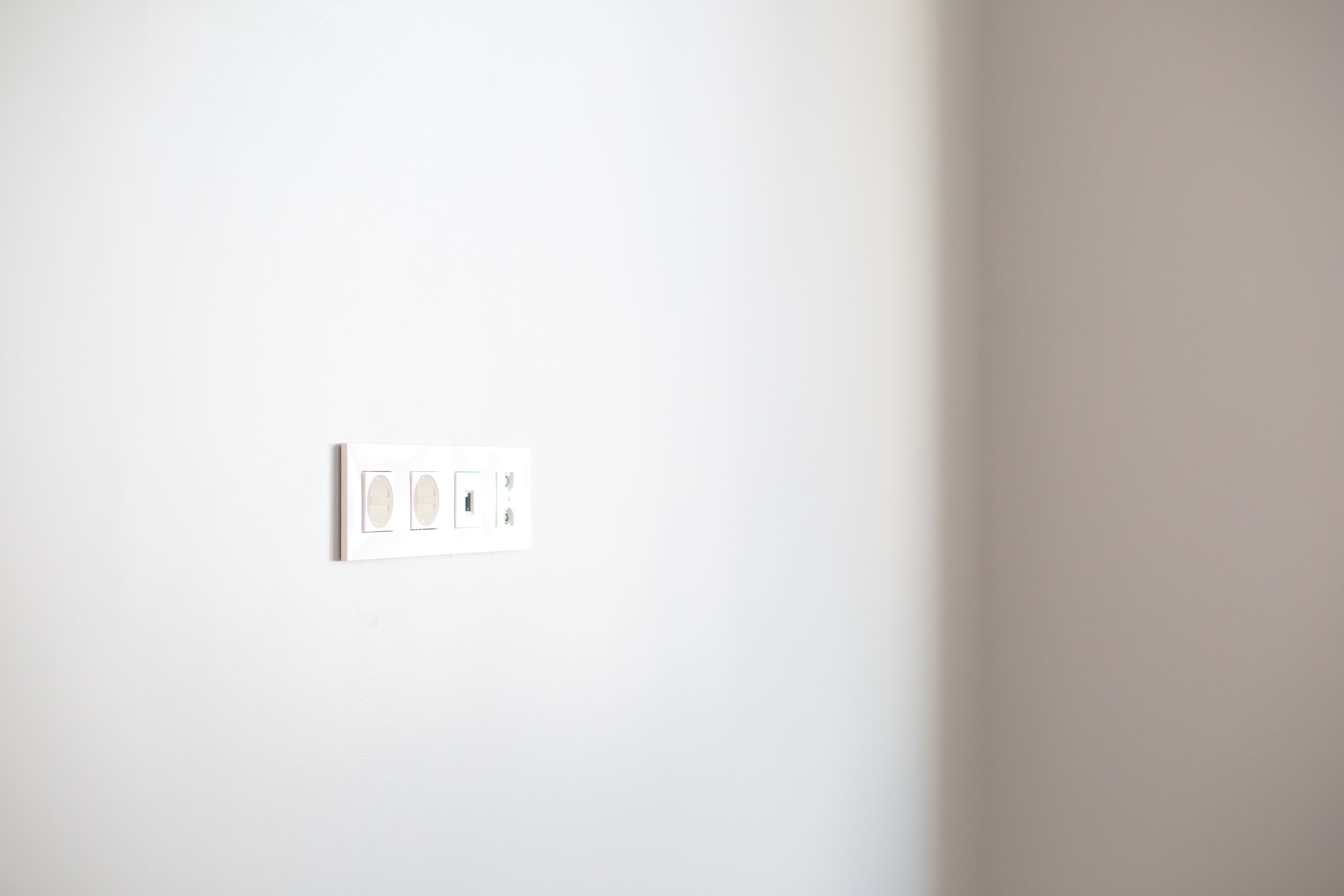 Close-up of a white wall featuring a modern electrical outlet, ideal for design concepts.