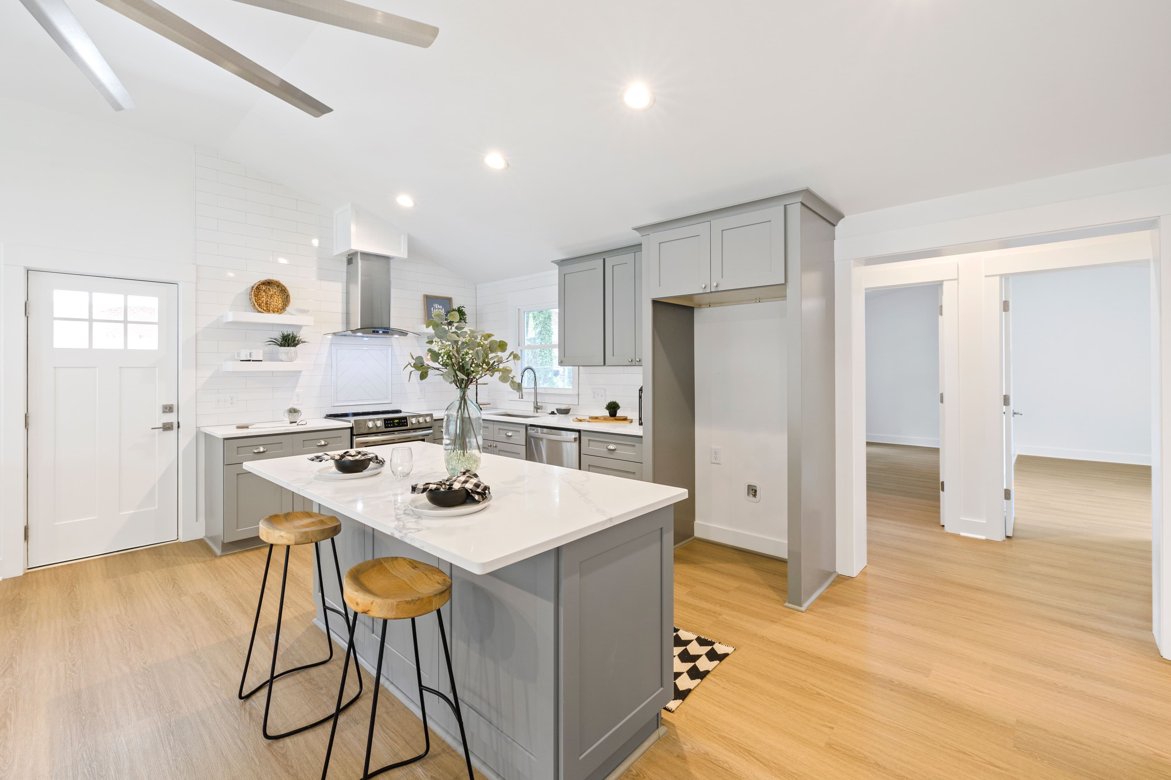 Bright kitchen interior featuring a marble island and wooden stools with minimalist design.