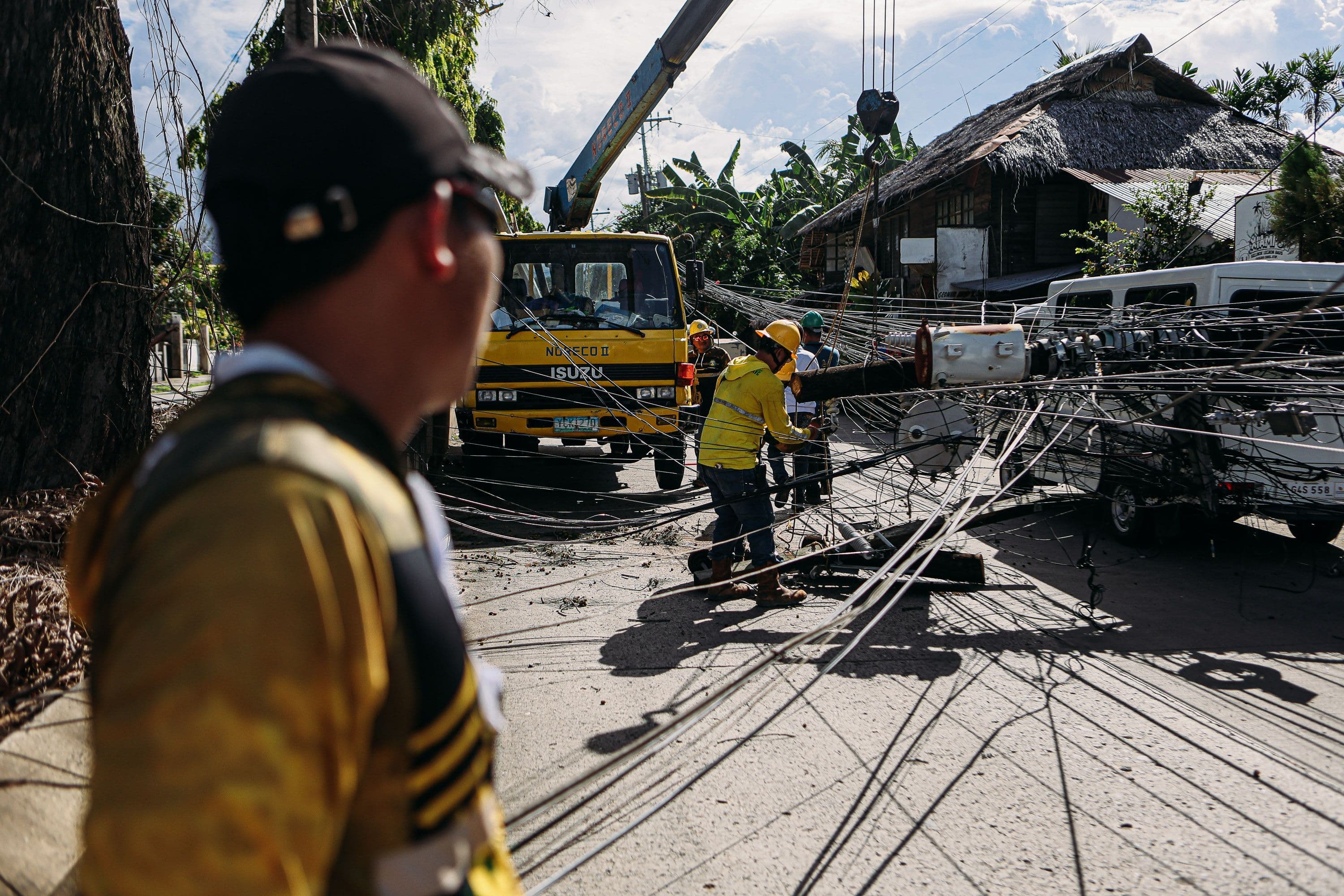 Utility workers assess and fix downed power lines on a sunny day, ensuring safety and service restoration.