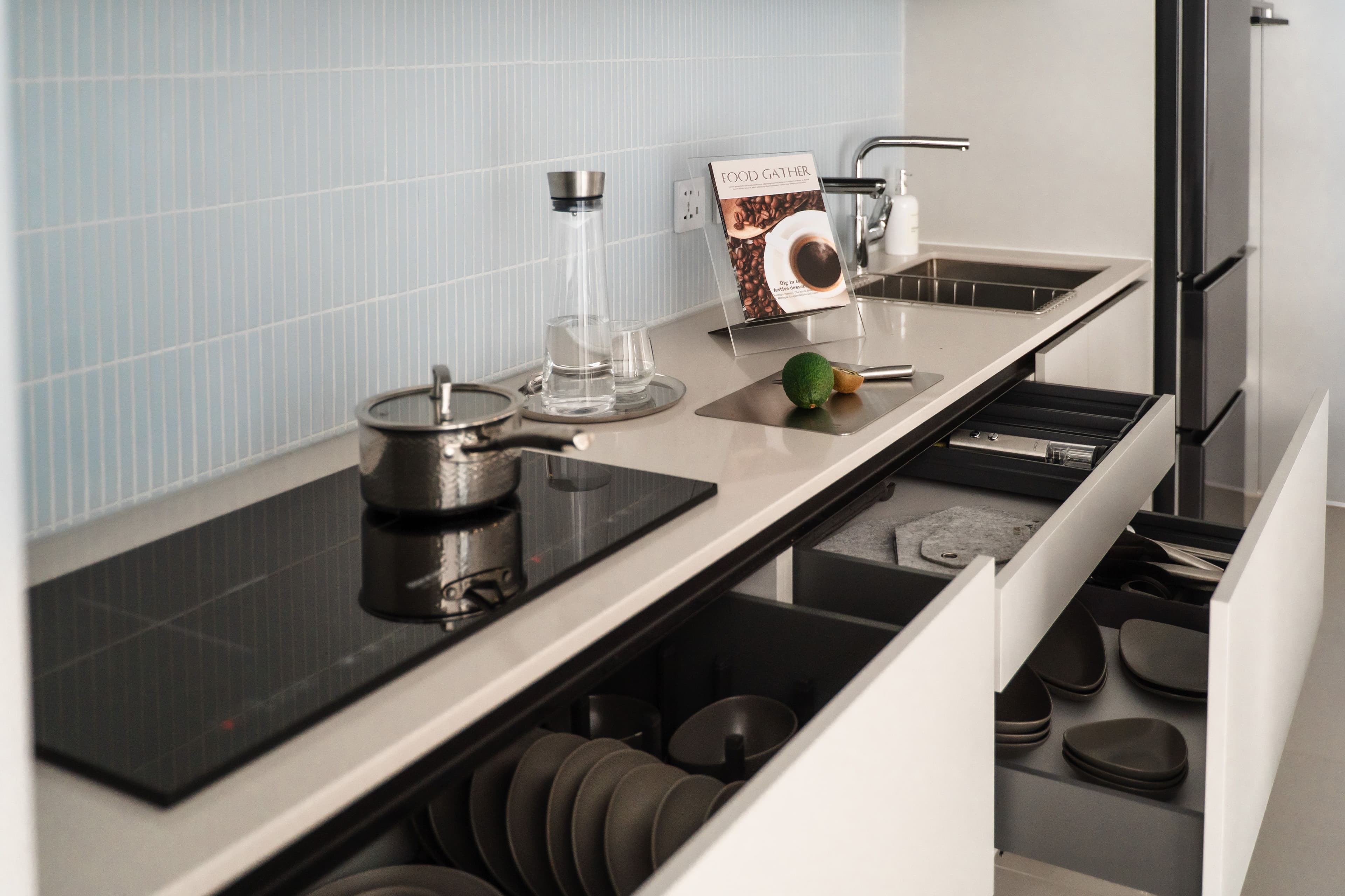 Sleek modern kitchen design with open drawers and induction stovetop highlighting contemporary style.