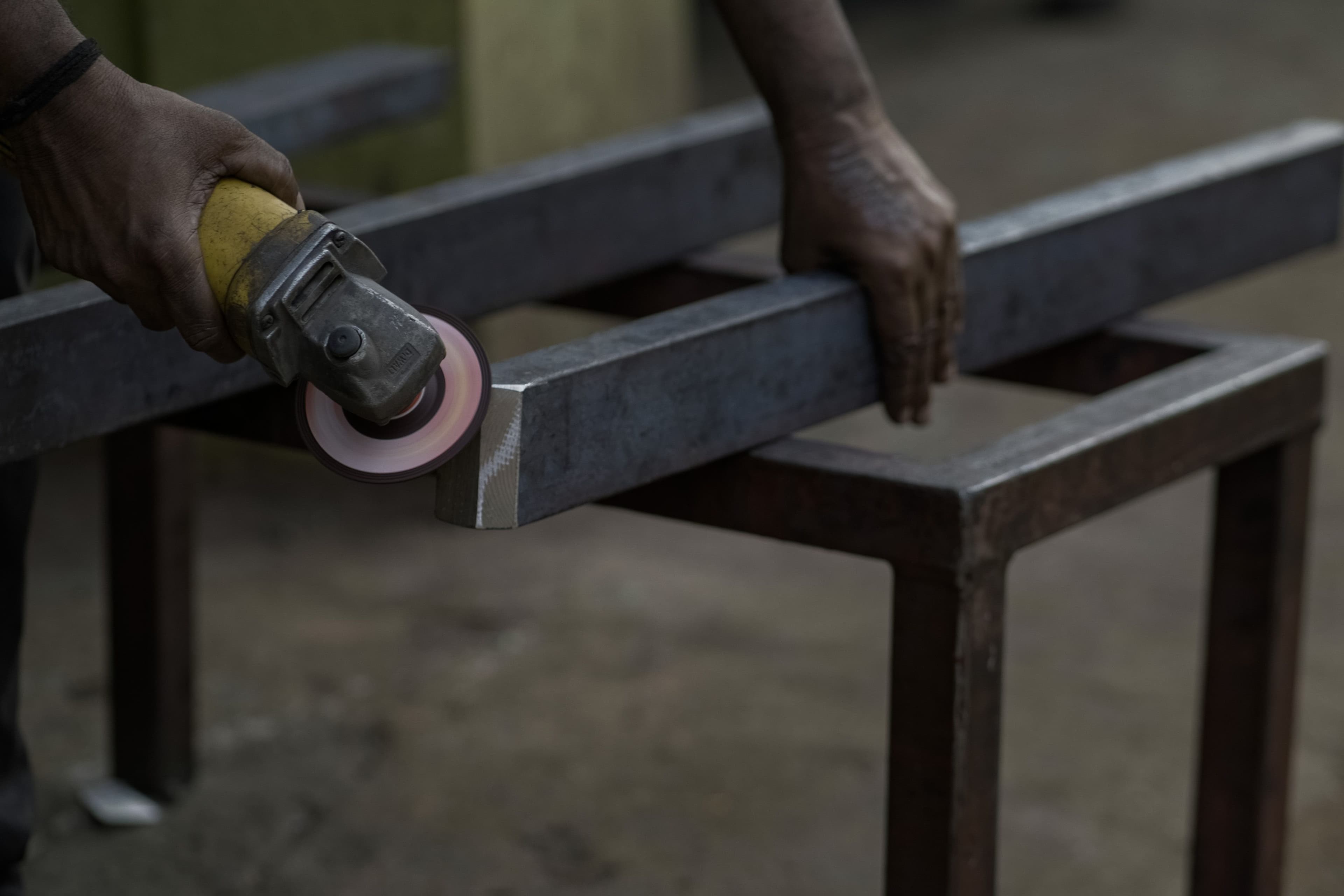 Close-up of a worker skillfully grinding metal on a workbench with an angle grinder.