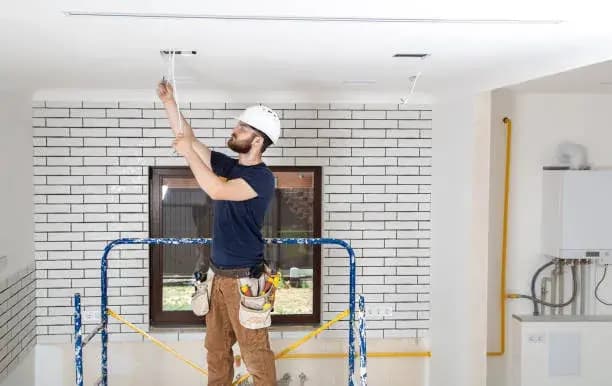Builder electrician at work, installing lamps at height.