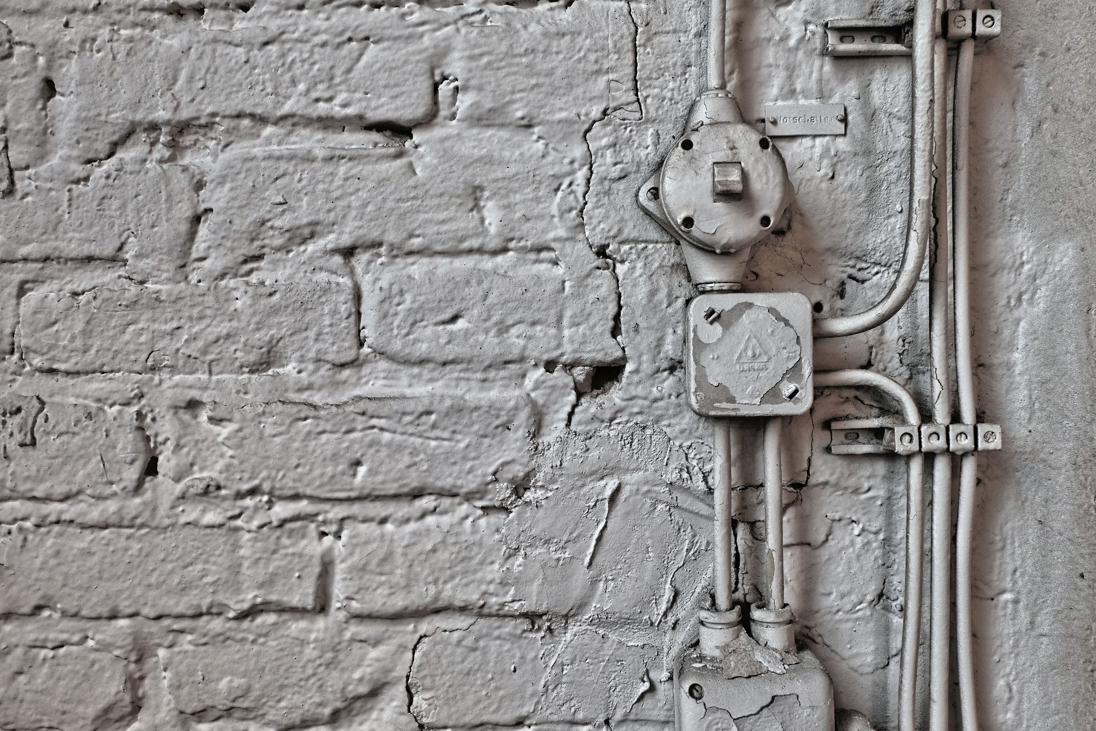 A vintage brick wall featuring aged electrical wires and boxes, showcasing industrial design.