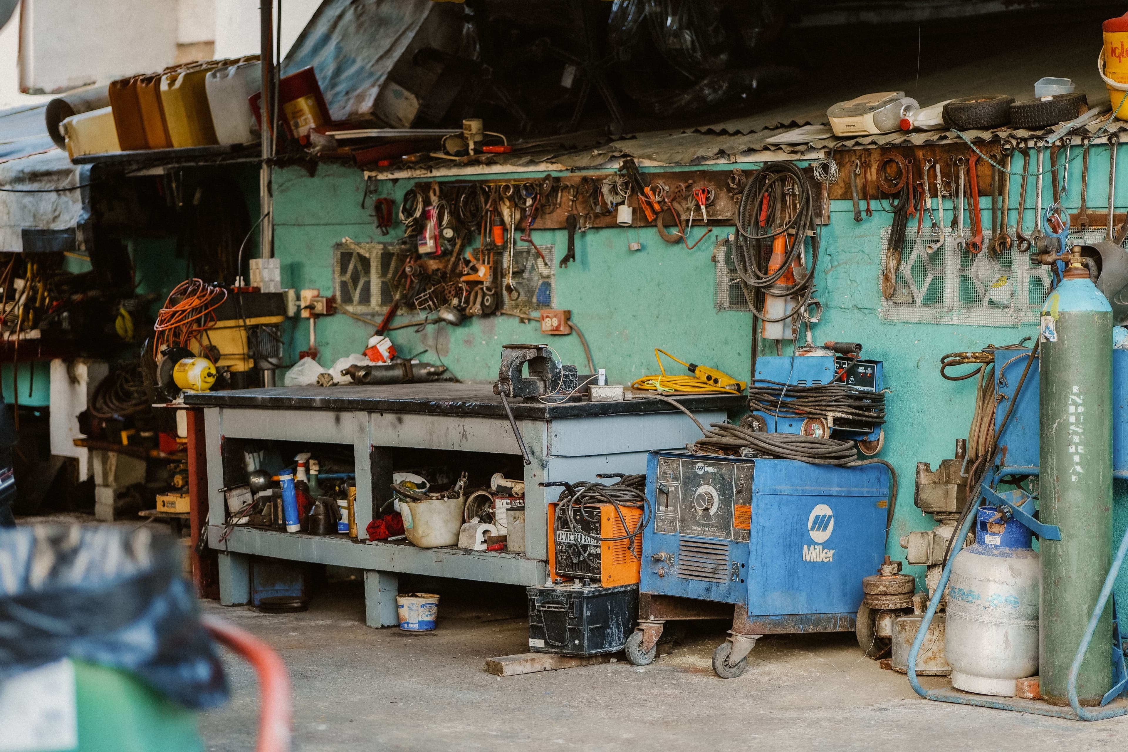 A cluttered workshop with tools, welding equipment, and storage solutions.
