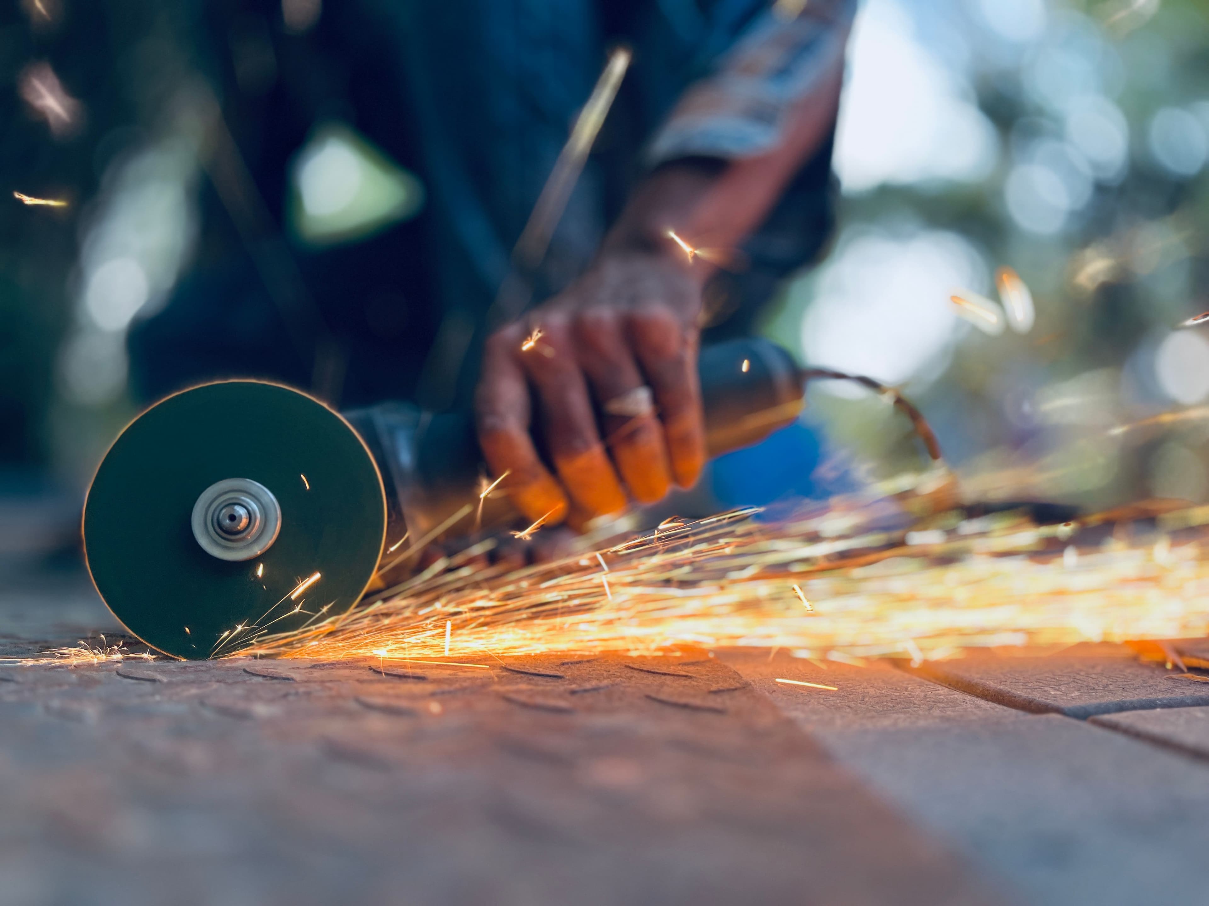 Dynamic shot of a man using an angle grinder with sparks flying. Perfect for industrial themes.