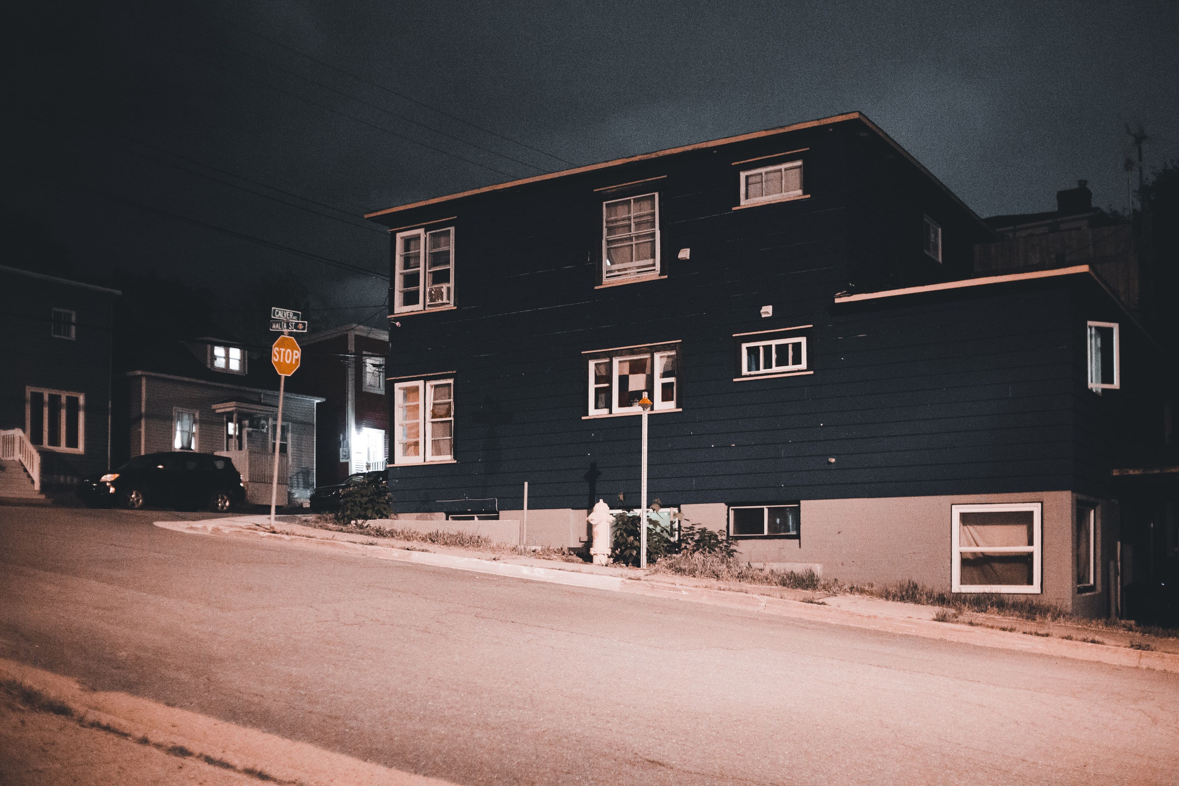 A serene nighttime view of urban residential houses on a quiet street with soft lighting and gentle ambiance.