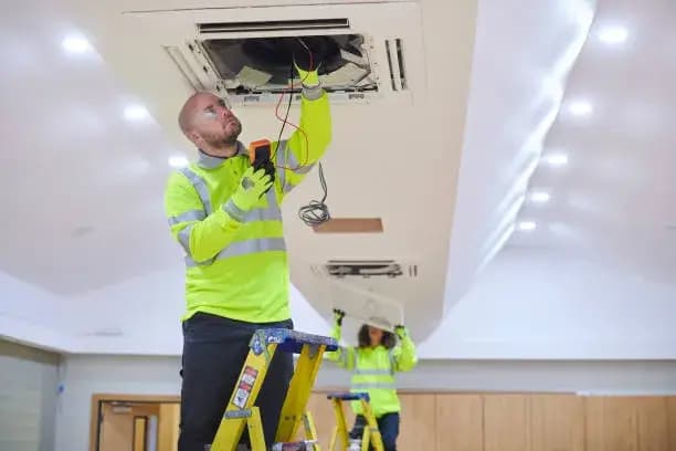 Technician inspecting ceiling fan installation.