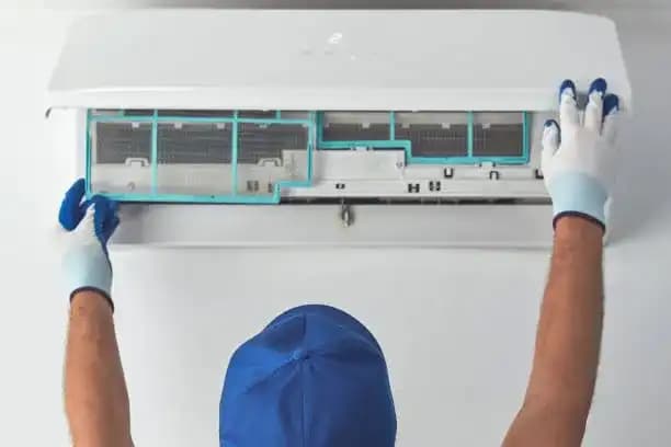 Repairman cleaning and repairing indoor air conditioning unit.