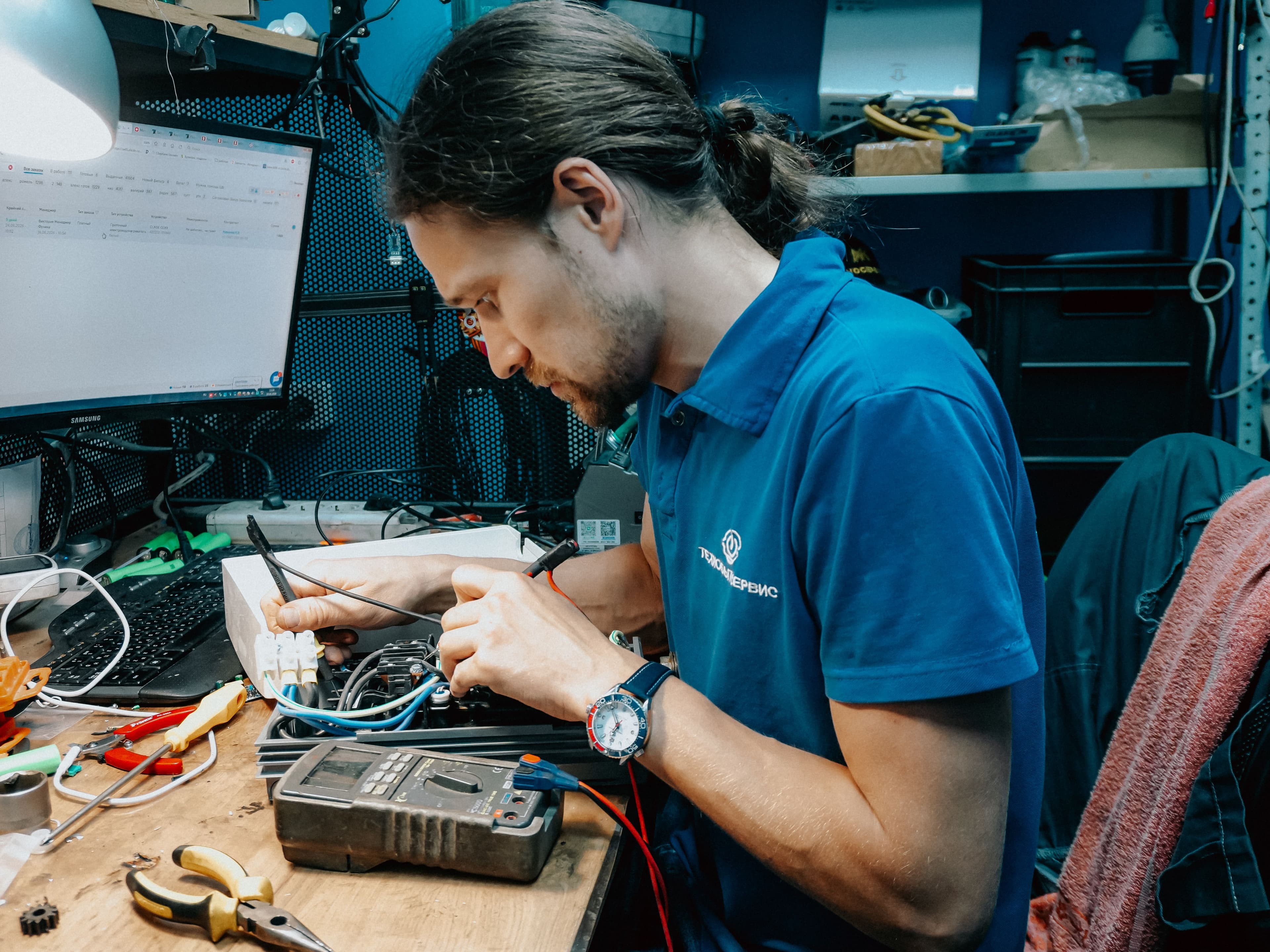 Focused technician mending electronics with tools in a modern workshop setting.