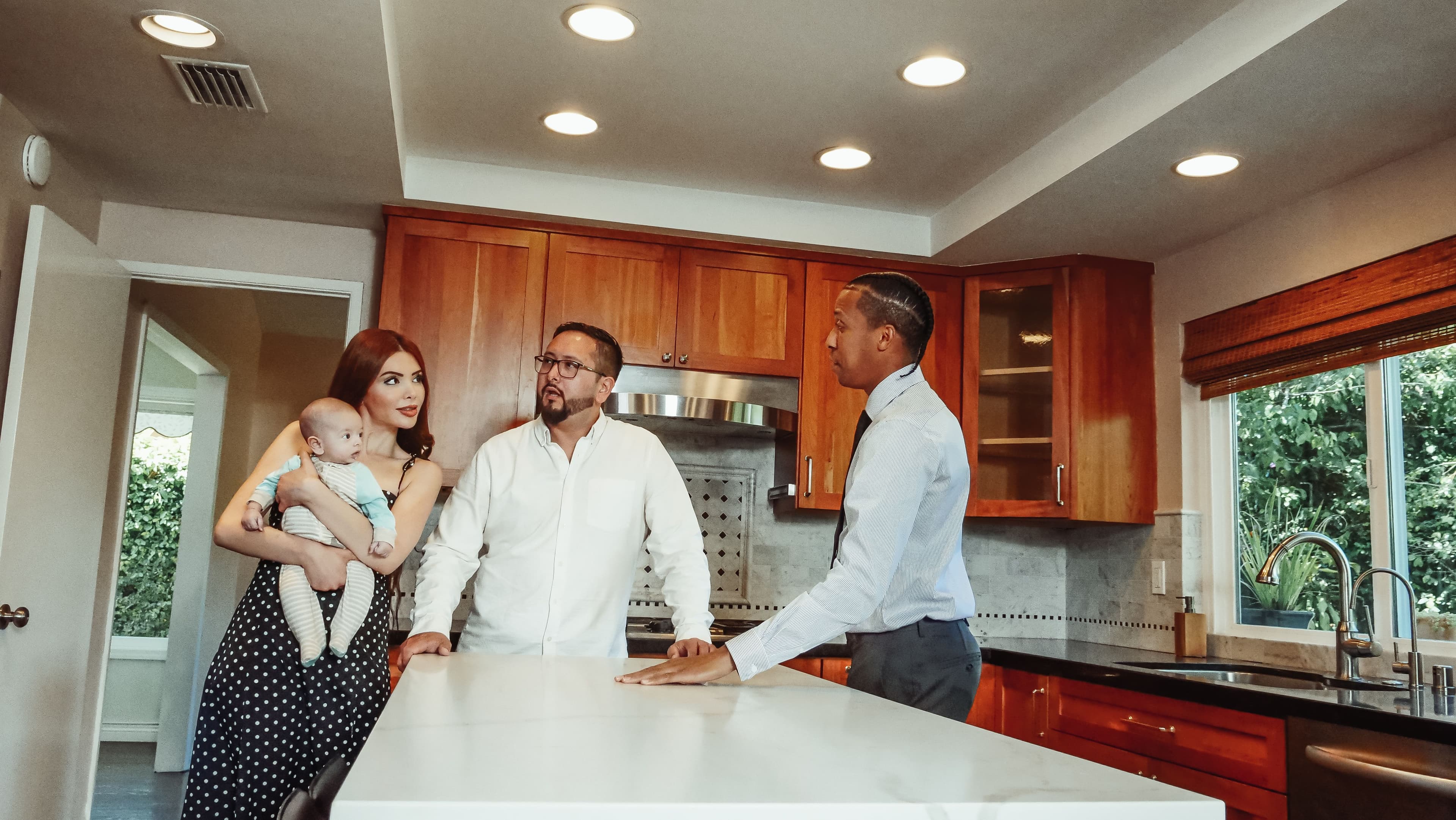 A young family tours a modern kitchen guided by a real estate agent.